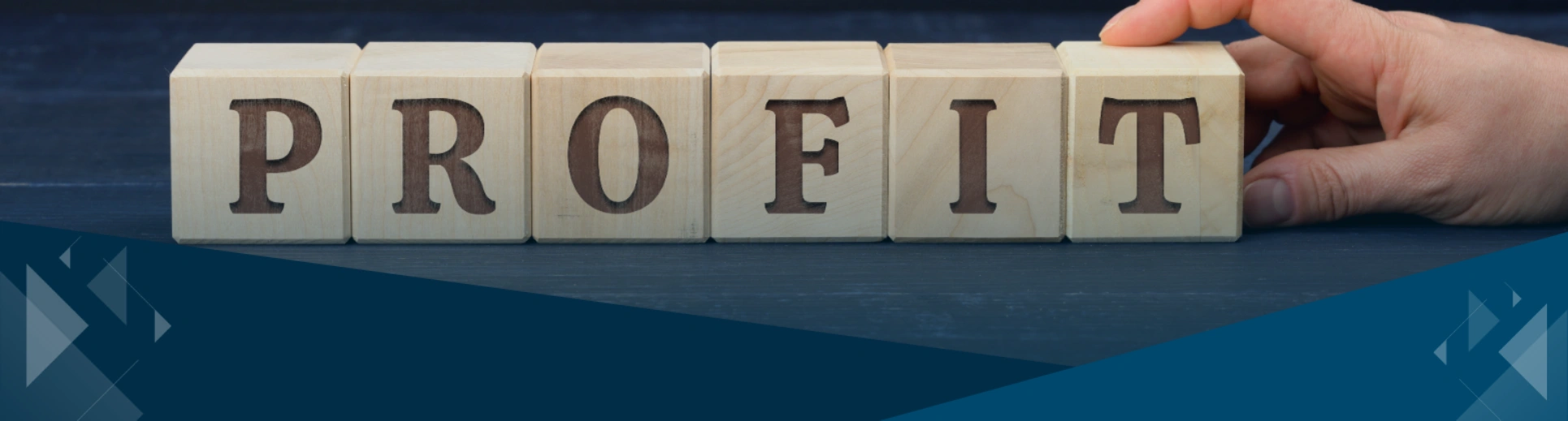 Wooden blocks spelling PROFIT with a hand adjusting the last block